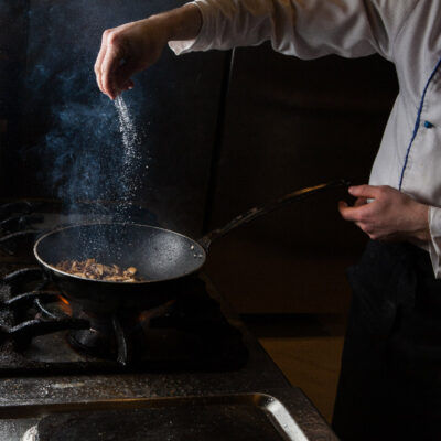 side-view-mushroom-frying-with-salt-fire-human-hand-pan side-view-mushroom-frying-with-salt-fire-human-hand-pan